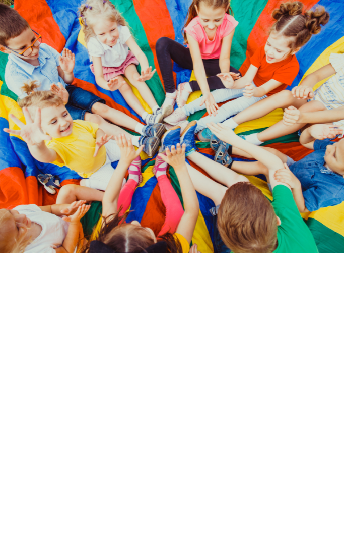 kids sitting inside of a parachute on the ground