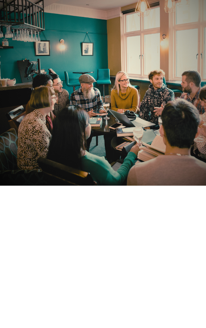 a group of people sitting around a table in a restaurant with books