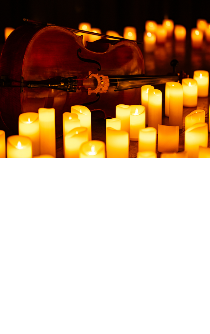 lit candles on a table with a violin on its side