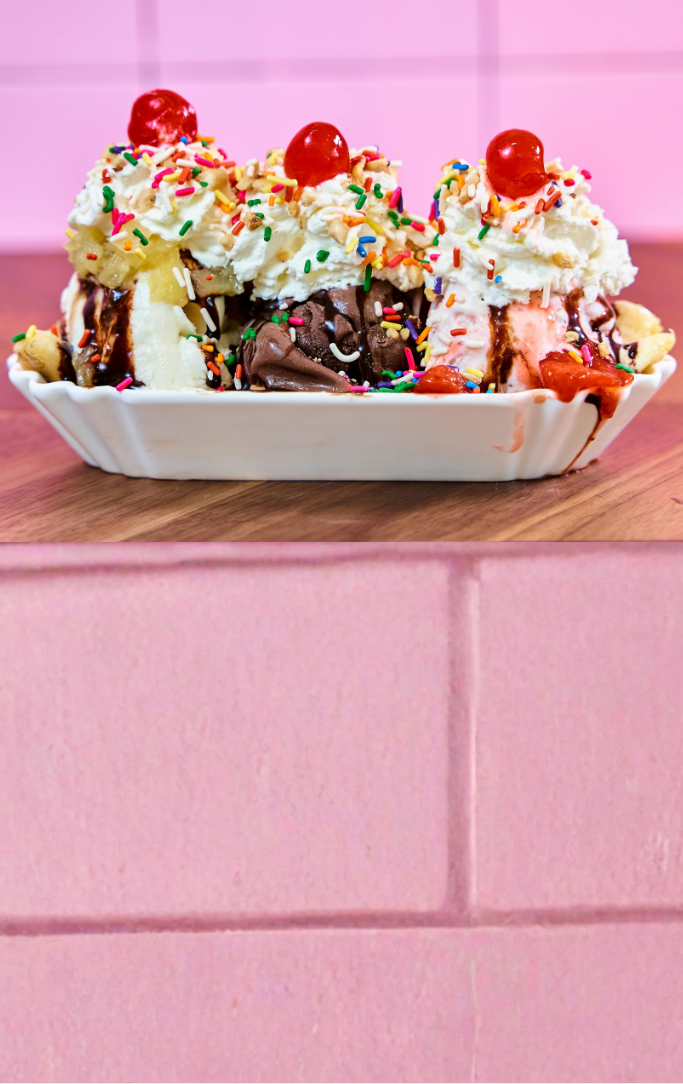a banana split tray with chocolate, vanilla, and strawberry ice cream with toppings